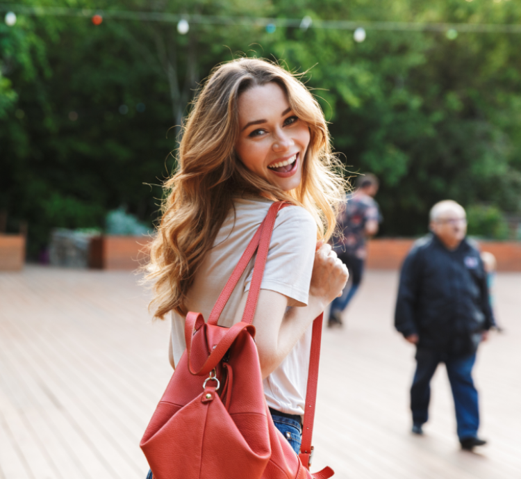 smiling-young-woman-with-backpack-walking-2021-08-26-18-23-14-utc
